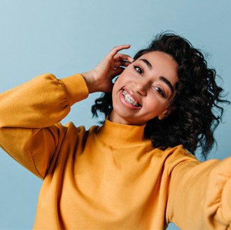 Girl in yellow sweater taking a selfie with her braces