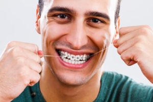 Closeup of smiling man flossing with braces