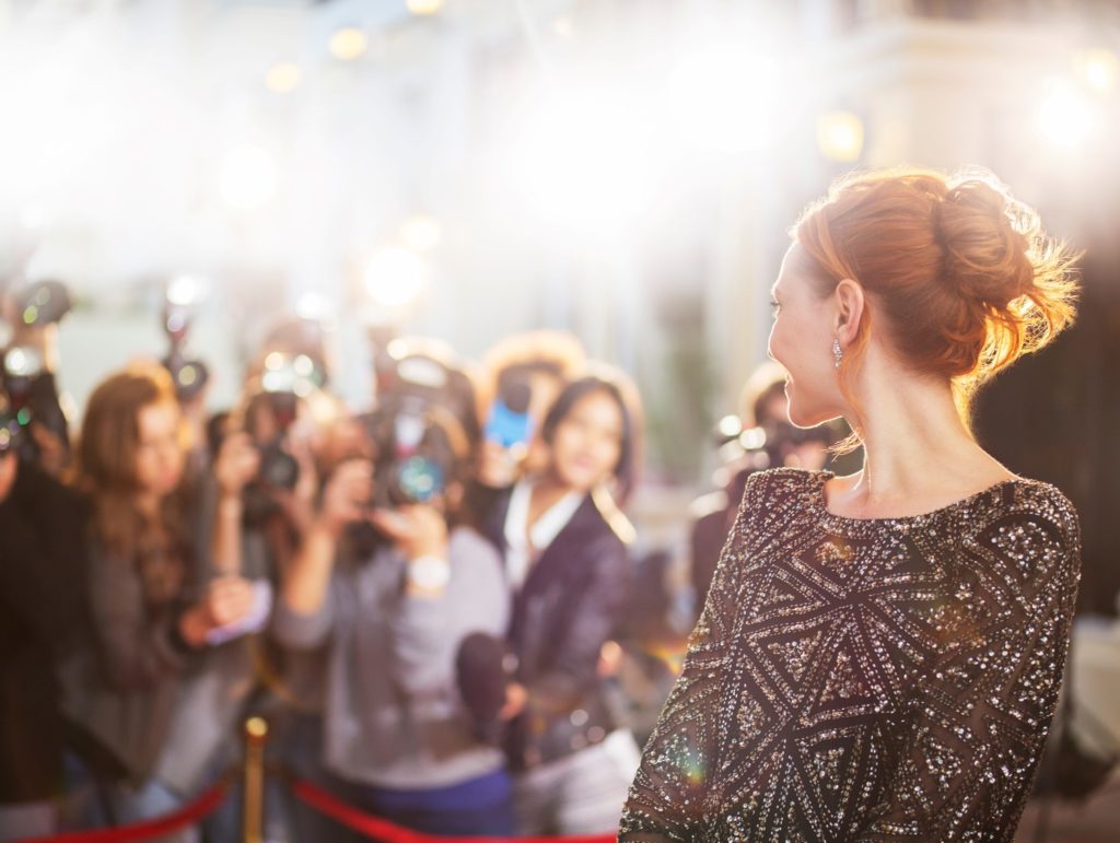 Celebrity smiling for cameras on red carpet