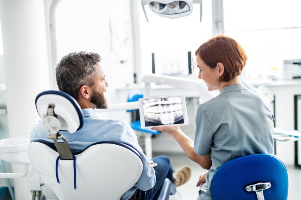 Smiling orthodontist showing patient X-ray