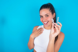 a person smiling and holding their Invisalign tray